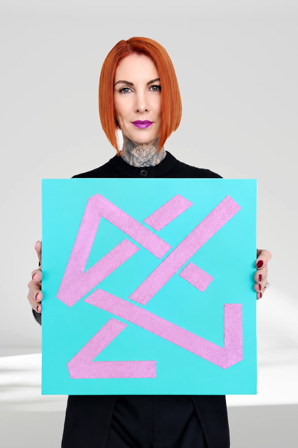 Nadine Vessey holding a turquoise and lilac geometric artwork